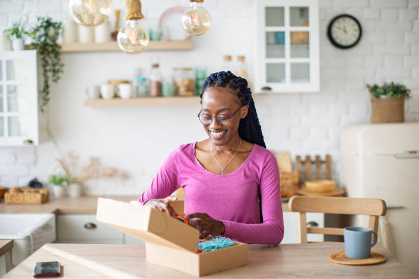 istock Young Black Woman Receiving Box And Unpacking It 1410774500