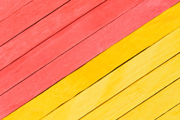 Bright yellow and red painted boards arranged diagonally. Wooden textured background. Textured straight planks in red and yellow.