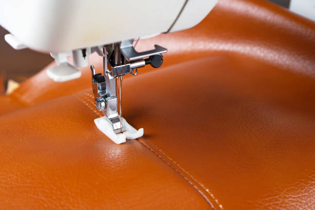 istock Modern sewing machine presser foot with a needle sews brown leather 1410779739
