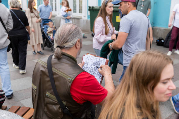 Saint Petersburg-Russia - 16.06.2022: Street artist. A person makes a drawing of people on the street.