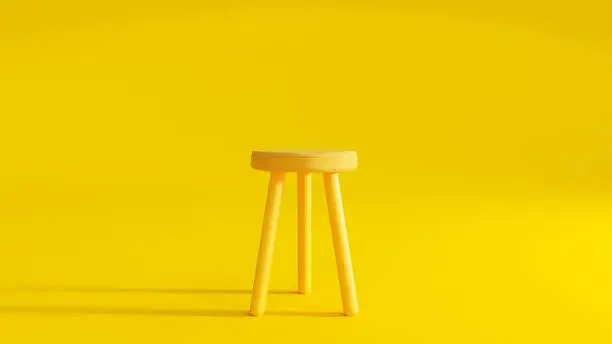 Photo of Yellow three legged chair on yellow background light from the side.
