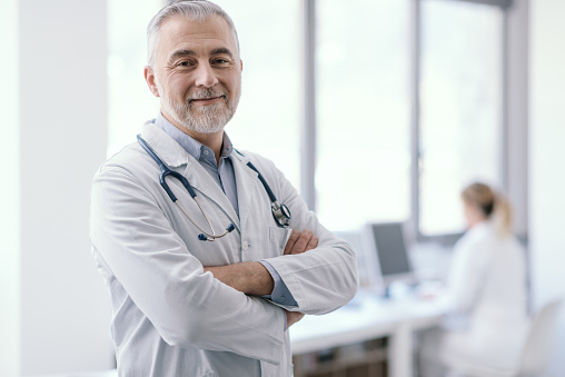 Confident doctor posing with arms crossed and smiling, healthcare and medicine concept