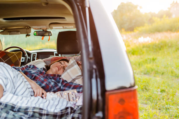 donna dorme comodamente la sua auto bagagliaio natura estate sotto coperta. concept caravanning viaggi gratuiti per il fine settimana. - comfortably foto e immagini stock