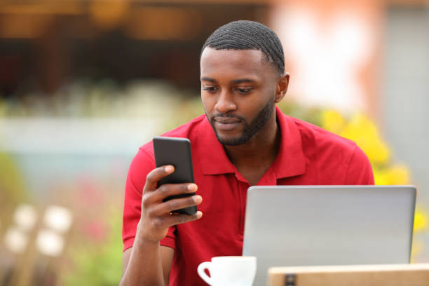 istock Black man in red using phone and laptop in a terrace 1410785344