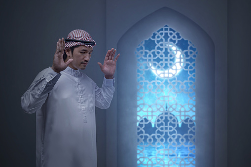 Muslim man with keffiyeh with agal in praying position (salat)