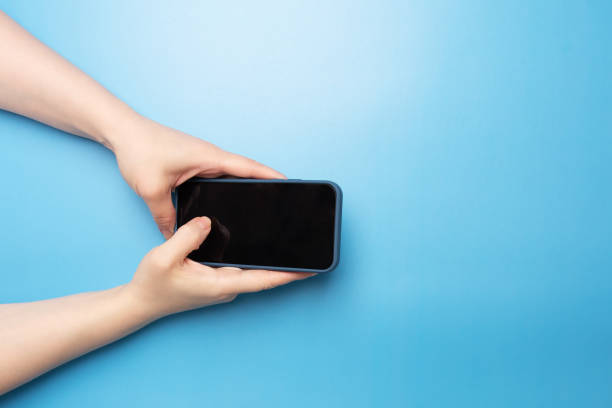 istock female hand with phone on blue background top view 1410786423