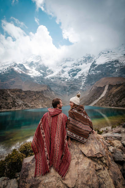 A young couple on vacation sitting on the rocks at Laguna Humantay, Peru A young couple on vacation sitting on the rocks at Laguna Humantay, Peru Sallqantay stock pictures, royalty-free photos & images