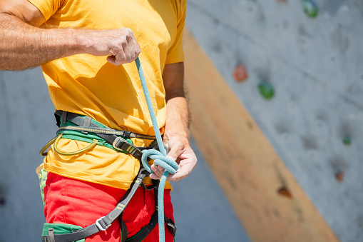 A climber knits a knot. A man prepares to climb a climbing route. Insurance and safety in rock climbing.