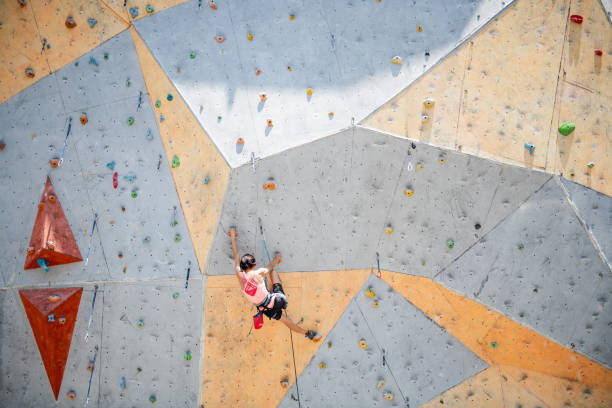 Sportswoman climber moving up on steep rock, climbing on artificial wall. Extreme sports and bouldering concept