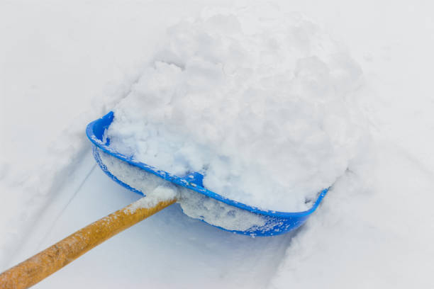 Cleaning fresh snow with blue plastic shovel outdoors in winter