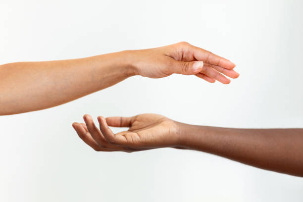 istock Hands with different skin colour, one african-american, one caucasian, touching each other on gary background. 1410792977