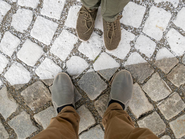 istock Two pairs of legs on paving stones. 1410794335