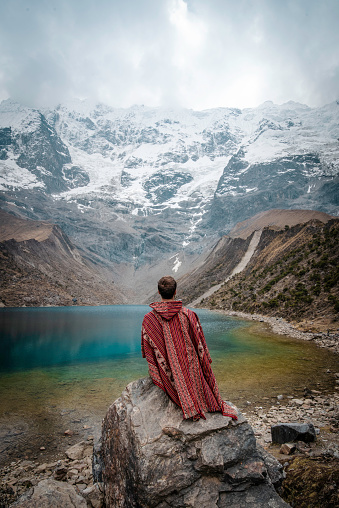 A young man with a poncho on vacation in Laguna Humantay, Peru