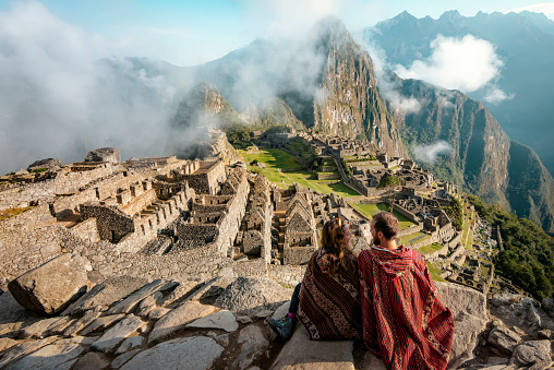 Pareja vestida de ponchos observando las ruinas de Machu Picchu, Perú photo