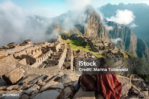 istock Couple dressed in ponchos watching the ruins of Machu Picchu, Peru 1410796651