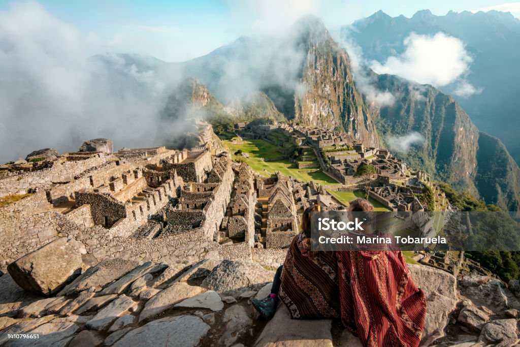 Couple dressed in ponchos watching the ruins of Machu Picchu, Peru Couple dressed in ponchos watching the ruins of Machu Picchu Peru Stock Photo