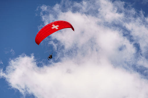 Twin Paraglider with a Red/White Swiss Flag Design in the Swiss Alps