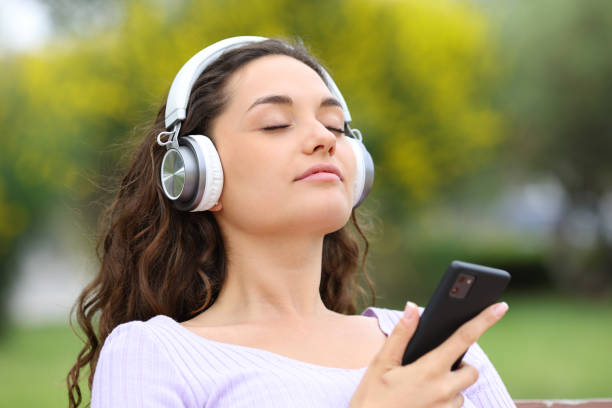 mujer meditando guía de escucha en un parque - chill out audio fotografías e imágenes de stock