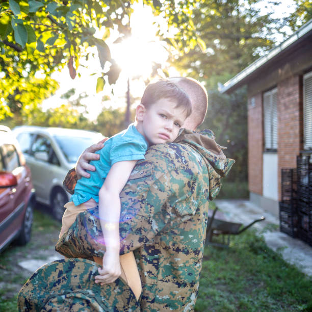 istock Little boy and soldier in a military uniform say goodbye before a separation. Back view of young father holding and embracing his son. 1410803833