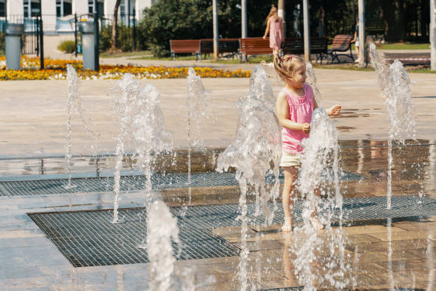 istock Happy kid playing in a fountain with water 1410807275