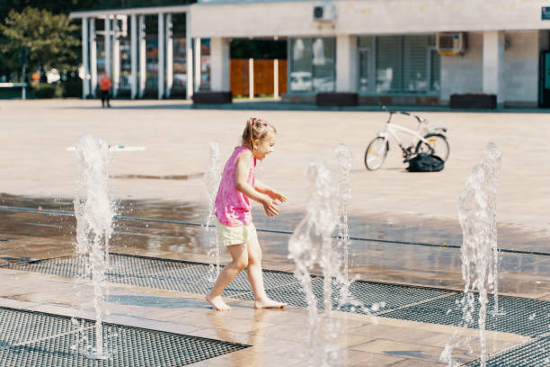istock Happy kid playing in a fountain with water 1410807336