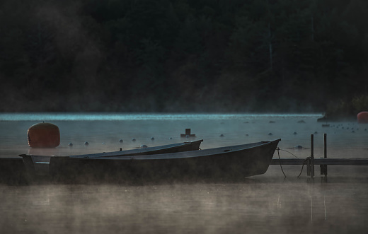 On a lake at dusk, boats and mist