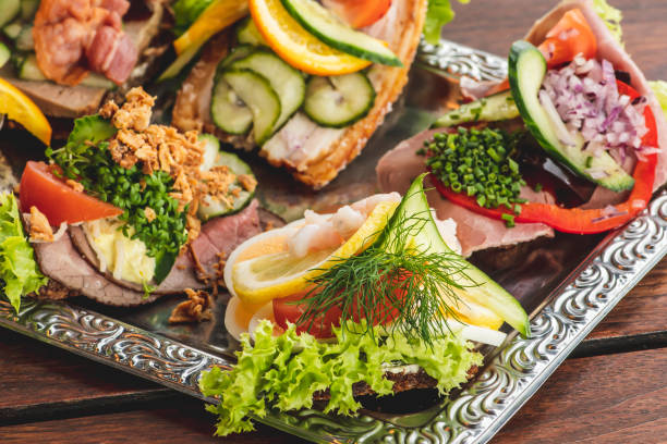 Danish traditional Smørrebrød or open sandwiches served in a plate Danish traditional Smørrebrød or open sandwiches served in a plate, roast beef with remoulade, tomato and shredded horseradish on Danish rye bread, egg, prawns, lemon and mayonnaise danish culture stock pictures, royalty-free photos & images