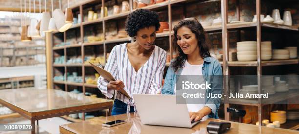Two Young Shop Owners Using A Laptop In Their Store Stock Photo - Download Image Now