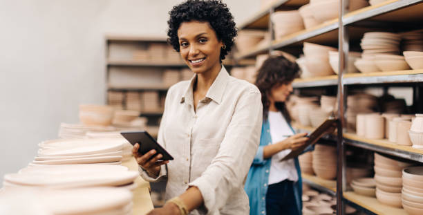 istock Cheerful female ceramist using a digital tablet in her shop 1410813009
