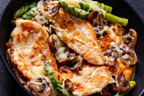 Chicken Madeira in frying pan, top view close-up of Chicken Madeira, juicy chicken breasts and mushrooms in a madeira cream sauce under melty mozzarella cheese and asparagus madeira sauce stock pictures, royalty-free photos & images