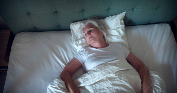 Anxious, mature woman trying to sleep at night. Dealing with sleeping disorder stock photo