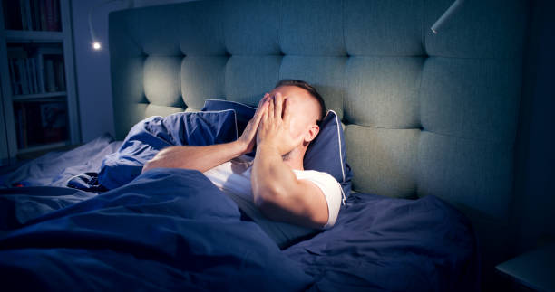 Frustrated man fighting with sleeping disorder. Holding head in hands stock photo