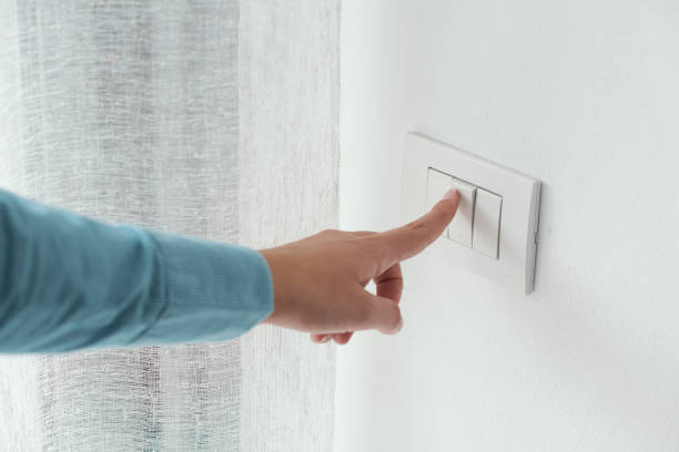 Woman pressing a light switch Woman pressing a light switch, energy saving concept switching stock pictures, royalty-free photos & images