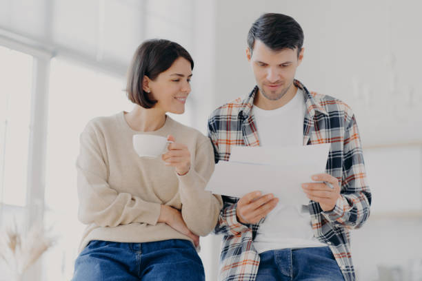 istock Serious couple study documents together, have serious looks, drink coffee, dressed in casual wear, plan their budget, pose in spacious light room, do paperwork, busy preparing financial report 1410817483