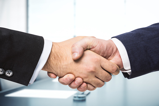 Business people shaking hands outside of office building.