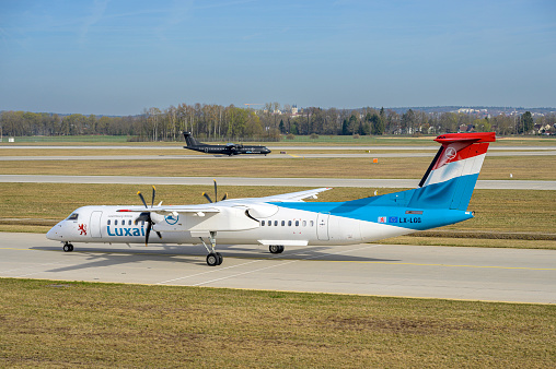 Munich, Germany - 22. April 2022 : Luxair Bombardier DHC-8-402Q Dash 8 with the aircraft registration OO-SSR \nis taxiing for take off on the northern runway 08L of Munich Airport MUC EDDM