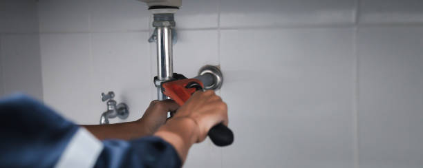 male plumber using wrench to fix leaking sink in home bathroom. - plumbline imagens e fotografias de stock