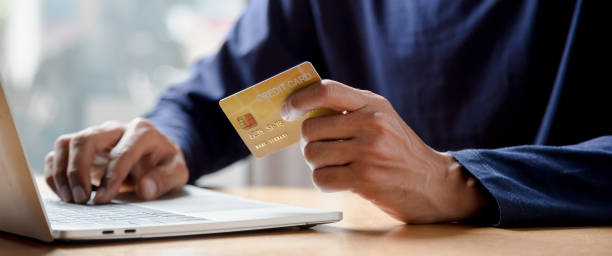 istock Man holding credit card and using smartphone at home online shopping ecommerce internet banking spend money work from home concept. 1410825125