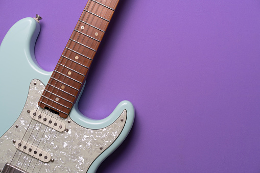 Electric guitar on purple table background, close up music concept