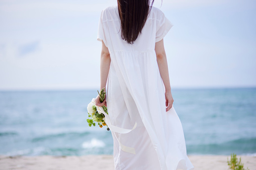 Wedding, couple and beach with a man and woman holding hands while walking on the sand by the ocean or sea. Love, trust and marriage with a bride and groom on the coast at sunset for celebration