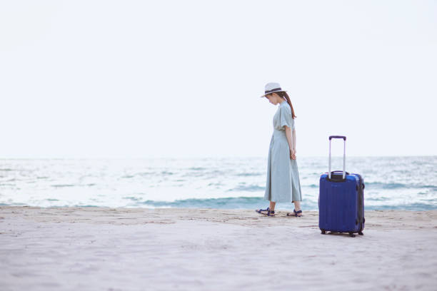 istock Japanese woman standing on the beach with a suitcase 1410825444