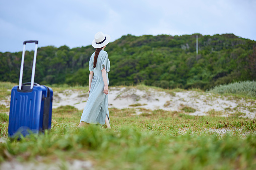 Japanese woman standing on the beach with a suitcase