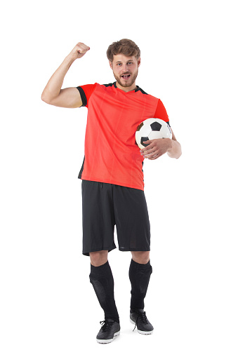 Professional soccer player looks confident in red sportwear and boots training, playing isolated over white studio background. Concept of game, sport, recreation, active lifestyle.