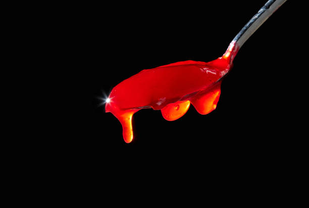 istock Red berry jam spoon isolated on black background. Cherry, raspberry, strawberry, currant jam. 1410831811