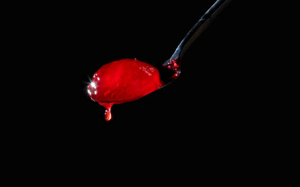 istock Red berry jam spoon isolated on black background. Cherry, raspberry, strawberry, currant jam. 1410831844