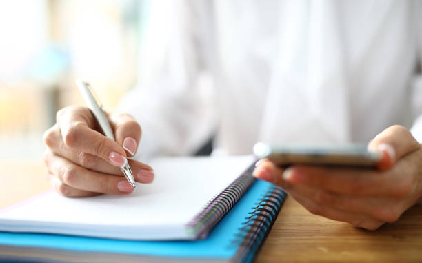 istock Closeup of freelancer hands with mobile phone working on finance 1410834373