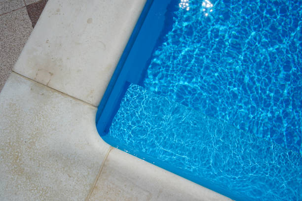 istock Swimming pool with blue water outdoors with stone gray edge, closeup. Top view. 1410835295
