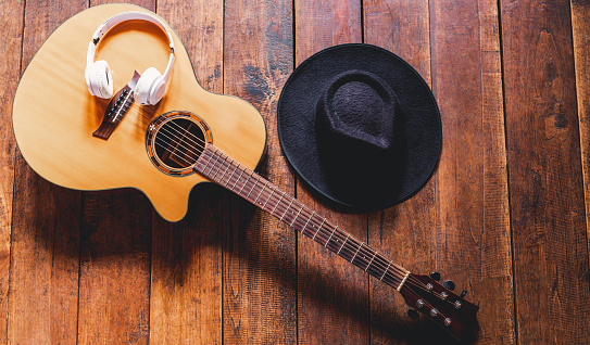 Top view acoustic guitars with earphones and hipster hats on old wooden background.Flat lay