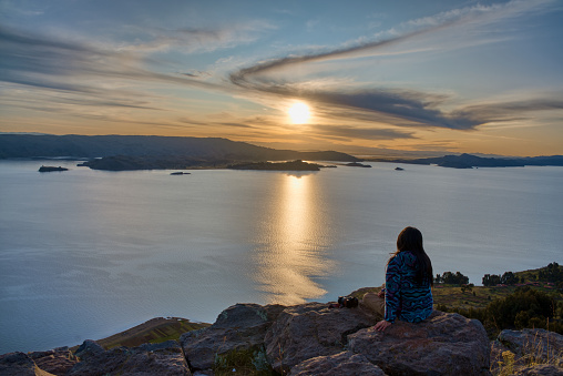 Tourist enjoy the sunset over Titicaca lake from Amantani island, Puno - Peru.