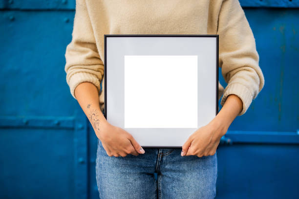 istock Mock up poster. Minimal template with empty picture frame mock up. Girl holding frame 1410843254